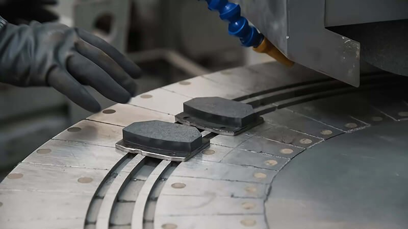 Brake pad production plant, A spacious facility with organized storage of brake pads and workers ensuring quality.